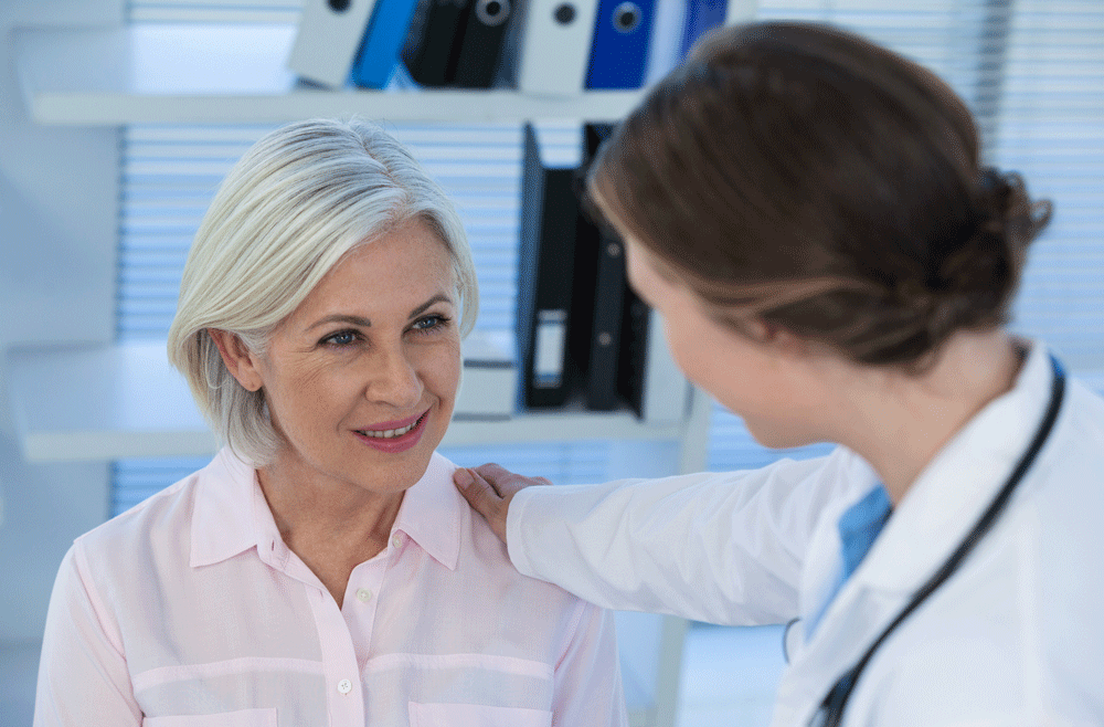 Older female patient smiling at female doctor